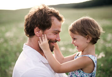 Handsome young father in green sunny summer nature holding his cute small daughter in the arms. - HPIF31095