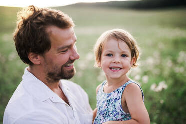 Handsome young father in green sunny summer nature holding his cute small daughter in the arms. - HPIF31098