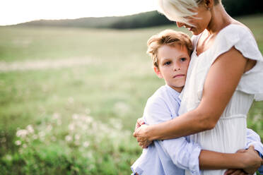 A small boy hugging his young mother outdoors in nature. A copy space. - HPIF31099