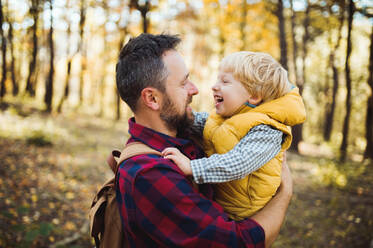 A mature father standing and holding a toddler son in an autumn forest, talking. - HPIF31134
