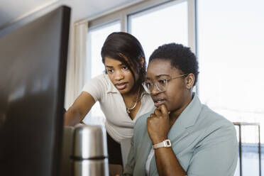 Female programmer discussing with colleague over computer in office - MASF36950