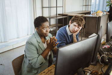 Tensed multiracial male and female programmers looking at computer monitor in creative office - MASF36968