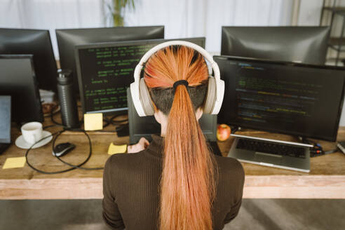 Rear view of female programmer working on laptop in creative office - MASF36971