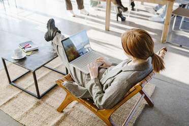 High angle view of businesswoman using laptop while sitting in chair at office - MASF36988