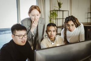 Multiracial programmers brainstorming over computer in creative office - MASF36998
