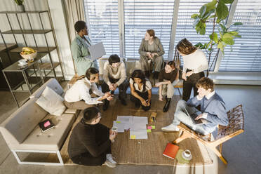 High angle view of multiracial male and female entrepreneurs discussing business strategy in meeting at creative office - MASF37015