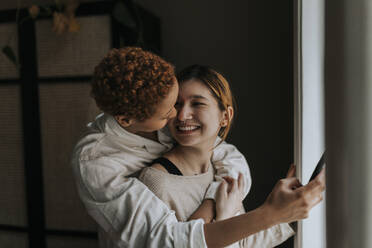 Happy non-binary couple embracing at home - MASF37069