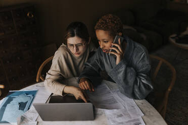 High angle view of non-binary couple doing finance on laptop at home - MASF37071