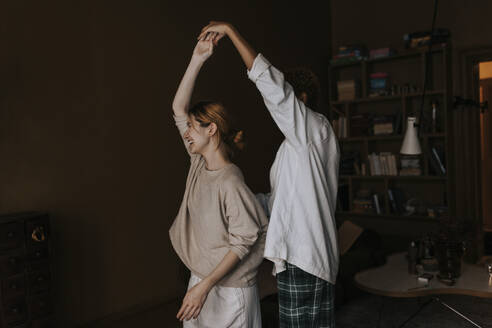 Carefree non-binary couple dancing with each other at home - MASF37082