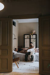 Couple in bedroom seen through doorway at home - MASF37097