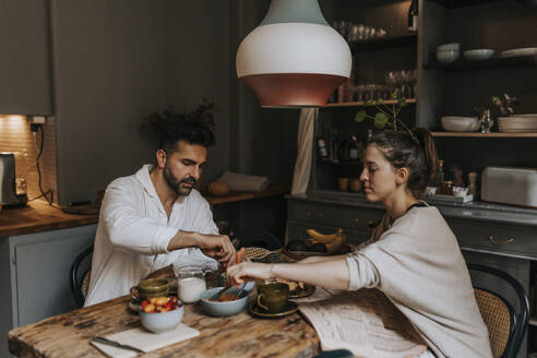 Couple having breakfast with each other at dining table in home - MASF37110