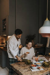 Couple reading newspaper while having breakfast at home - MASF37112