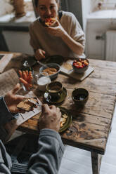 High angle view of man spreading peanut butter on bread while having breakfast at home - MASF37115