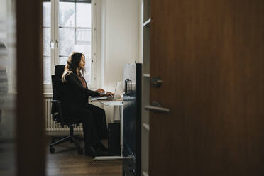 Female entrepreneur sitting on chair and working at office - MASF37124