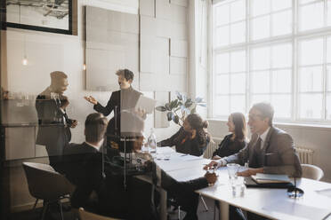 Male and female entrepreneurs discussing during business meeting in board room at office - MASF37129