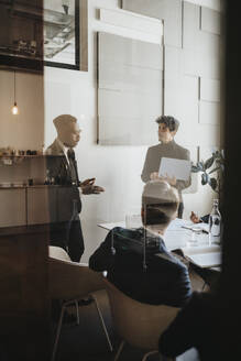 Businessman planning strategy with colleagues in board room seen through glass - MASF37131