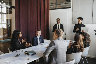 Female entrepreneur discussing with colleagues in business meeting at office - MASF37134