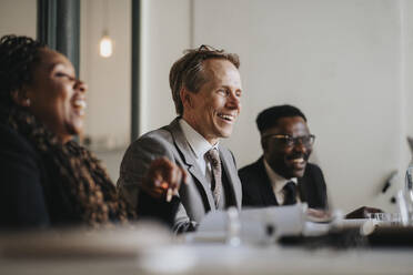 Smiling businessman discussing with colleagues during meeting at office - MASF37143