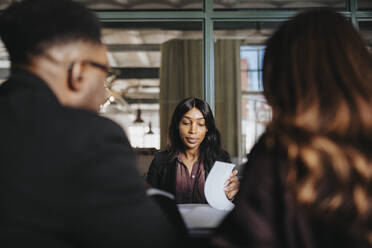 Female entrepreneur reviewing document in business meeting at office - MASF37152