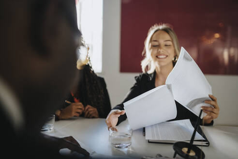 Smiling businesswoman reading agreement sitting in board room at office - MASF37153