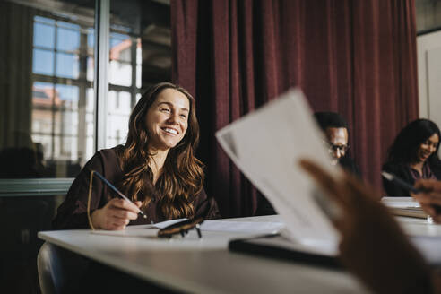 Smiling businesswoman discussing with colleague during meeting in board room at office - MASF37158