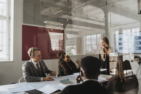 Happy male and female entrepreneurs during business meeting at office seen through glass - MASF37160