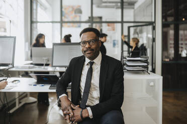 Portrait of mature businessman sitting at corporate office - MASF37188