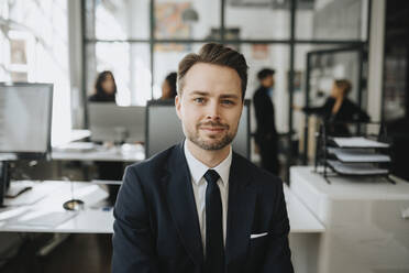 Portrait of male entrepreneur wearing black blazer at office - MASF37191