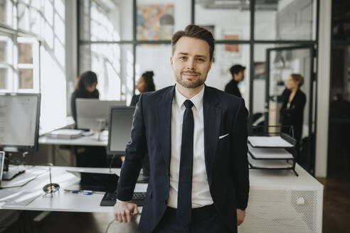 Portrait of smiling businessman wearing blazer standing at office - MASF37192