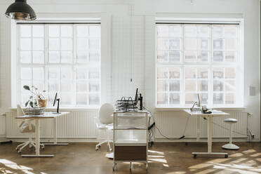 Empty corporate office with computers on desk near window - MASF37207