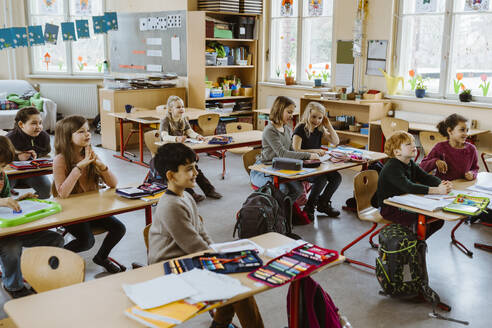 Male and female students attending lecture in classroom at school - MASF37214