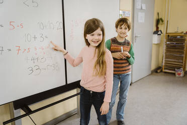 Happy girl solving maths problem with boy in classroom - MASF37276