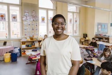 Female primary school teacher standing in a classroom gesturing to