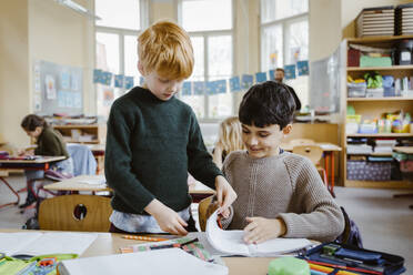 Boys sharing book while learning in classroom - MASF37279