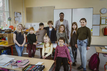 Portrait of smiling teacher and students against whiteboard in classroom - MASF37286