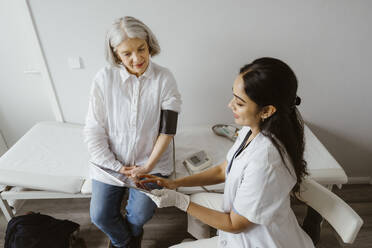 Doctor discussing with senior patient over tablet PC at clinic - MASF37306