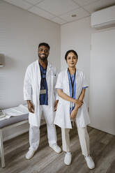 Portrait of confident male and female healthcare workers standing in consulting room - MASF37329