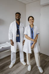 Smiling male and female medical colleagues standing in consulting room - MASF37330