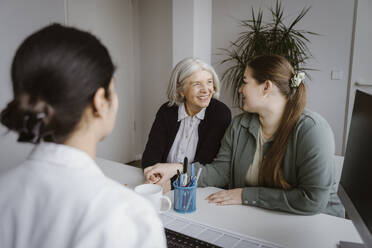 Daughter talking to mother during consultation with doctor in clinic - MASF37343