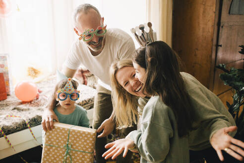 Cheerful parents and boy giving birthday present to girl at home - MASF37411
