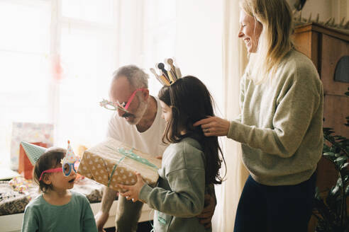 Parents and children with birthday present enjoying party at home - MASF37412