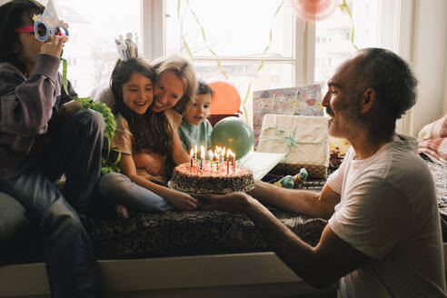 Happy family celebrating birthday with cake at home - MASF37420