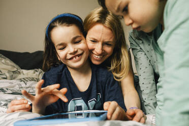 Happy woman with sons using digital tablet at home - MASF37426