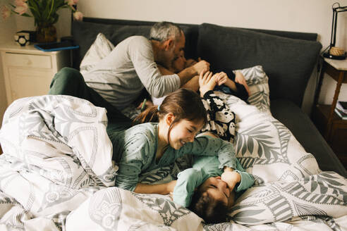 High angle view of happy family enjoying with each other on bed at home - MASF37428