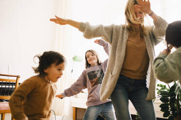 Happy woman dancing and enjoying with children at home - MASF37433