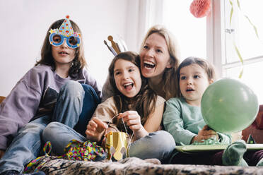 Cheerful mother with children enjoying birthday party at home - MASF37442