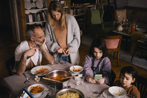 Family with spaghetti using smart phones at dining table - MASF37445