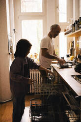 Father and son doing chores in kitchen at home - MASF37446