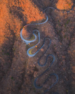 Aerial view from Kurokami-Daira viewpoint of a winding road during koyo season at sunrise, Nikko, Japan. - AAEF18209