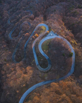 Aerial view from Kurokami-Daira viewpoint of a winding road during koyo season at sunrise, Nikko, Japan. - AAEF18210